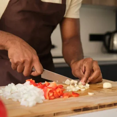 Sobre nosotros: Un cocinero picando verduras sobre una tabla de picar