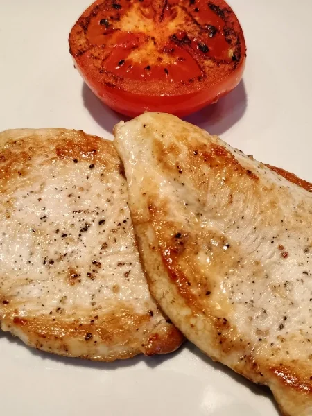 Dos filetes de pechuga de pollo a la plancha con tomate asado.