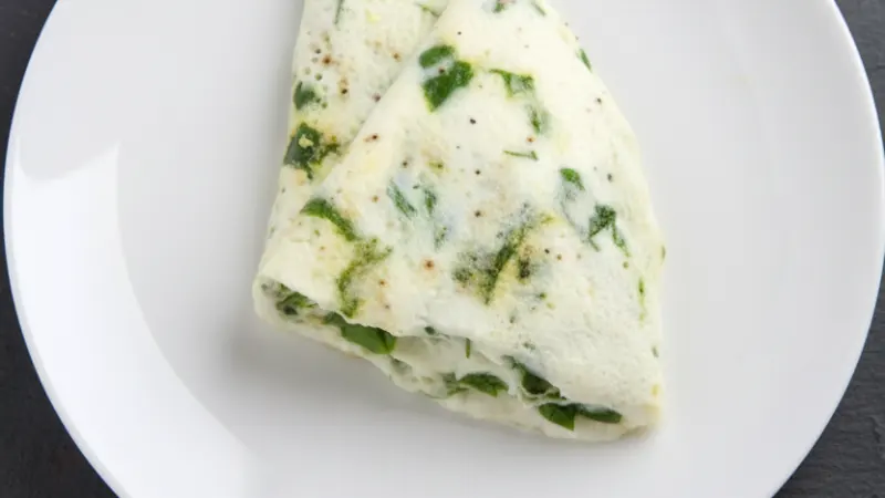 Una tortilla de claras con espinacas en un plato blanco
